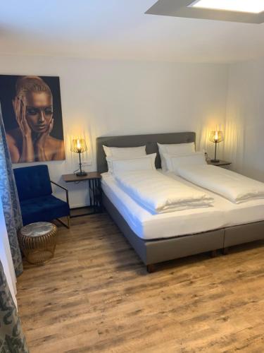 a bedroom with two beds and a blue chair at CityApartments Residence klimatisiert in Friedrichshafen