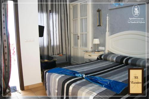 a bedroom with a bed with a blue and white comforter at La Posada Del Infante in La Puebla de los Infantes