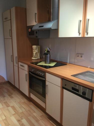 a kitchen with white cabinets and a stove top oven at Ferienwohnung Elsterveilchen 100 m bis zur Soletherme und Theater in Bad Elster