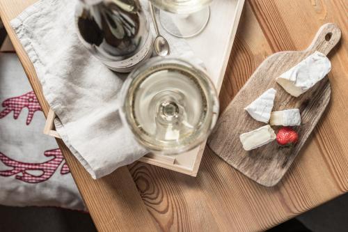 a wooden table with a tray with a glass of wine and cheese at Villa Adamo & Relax in Zakopane