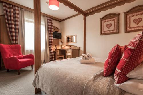 a bedroom with a large bed and a red chair at Villa Adamo & Relax in Zakopane