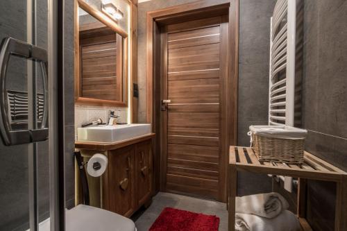 a bathroom with a sink and a toilet and a mirror at Villa Adamo & Relax in Zakopane