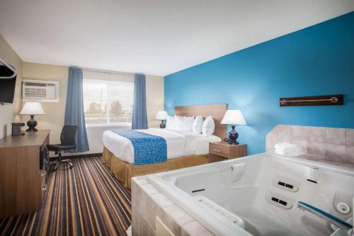 a hotel room with a bed and a bath tub at Travelodge by Wyndham Wahpeton in Wahpeton