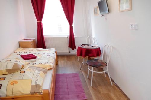 a bedroom with two beds and a table and a window at Fehér Hajó Panzió és Vendéglő in Győr