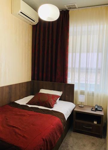 a bedroom with a bed with a red blanket and a window at Status Hotel in Poltava