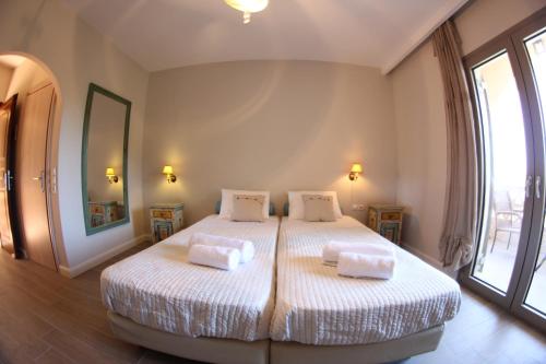 Un dormitorio con dos camas y una gran ventana. en Eleas gi (Olive Grove Estate), en Tsilivi
