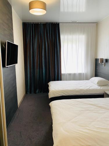 a hotel room with two beds and a window at Status Hotel in Poltava