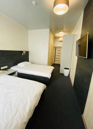 a hotel room with two beds and a tv at Status Hotel in Poltava