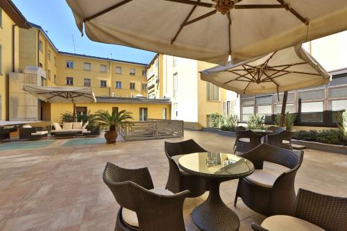 an outdoor patio with tables and chairs and umbrellas at Hotel Cappello D'Oro, BW Signature Collection in Bergamo