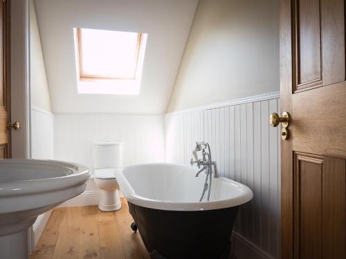 a bathroom with a bath tub and a toilet at The Gatehouse at Mullans Bay in Kesh