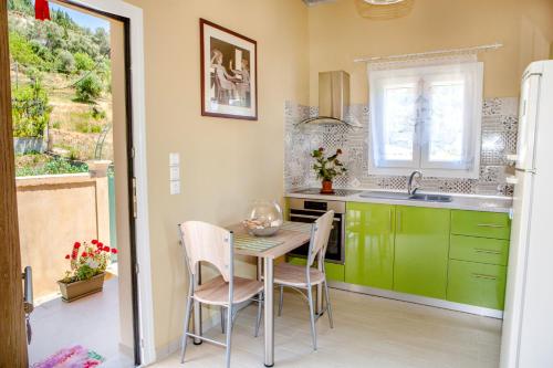 een keuken met groene kasten en een tafel en stoelen bij FilipposResort in Agios Gordios