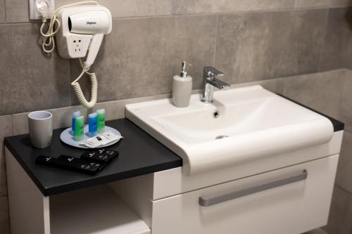 a bathroom with a white sink and a phone at Annona Apartments in Bečej