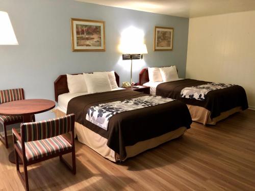 Habitación de hotel con 2 camas y mesa en The Budget Inn Express, en Sheridan