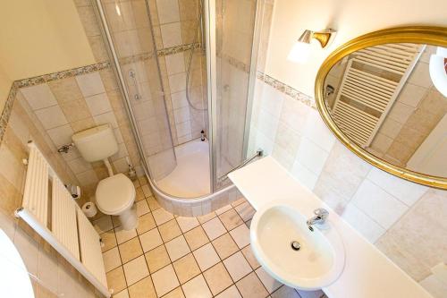 een badkamer met een wastafel, een toilet en een spiegel bij Ferienhaussiedlung Strandperlen Buchenhof 4a (Typ IV) in Wustrow