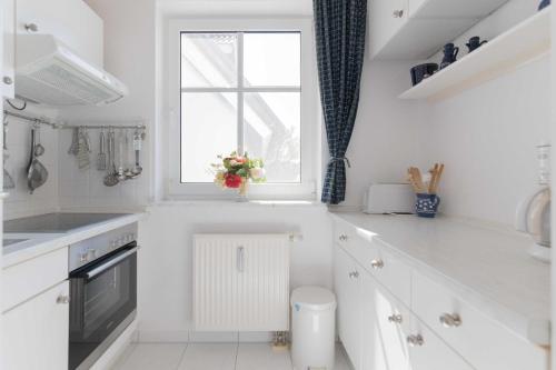 a white kitchen with a window and a white counter at Haus zum Strand HAUS ZUM STRAND Whg 2.2 in Wustrow