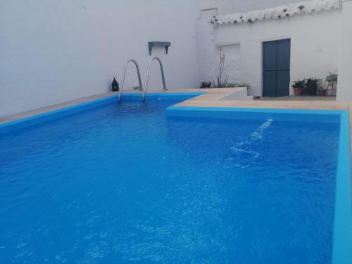 a swimming pool with blue water in front of a white building at Casa Rural Casa Ronda in El Bosque