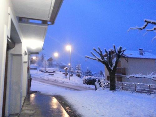 a snow covered street at night with a tree and street lights at Hôtel Le Beauséjour in Saint-François-Longchamp