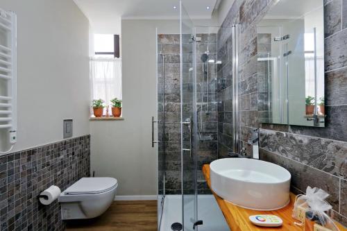 a bathroom with a sink and a glass shower at Il Borgo Luxury Suites in Nettuno