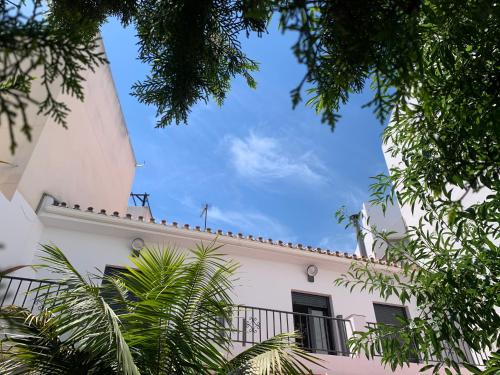 a white building with a balcony and trees at NerjaRooms in Nerja