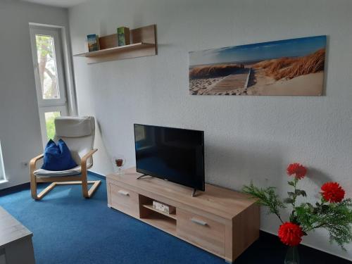 ein Wohnzimmer mit einem Flachbild-TV und einem Stuhl in der Unterkunft DA Ferienwohnungen in Bargischow