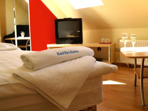 a hotel room with a bed with a tv and towels at Hotel Pension Kirschstein in Wolgast