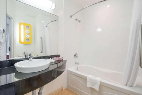 a white bathroom with a sink and a tub and a sink at Motel 6-Kingston, ON in Kingston