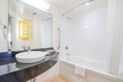 a white bathroom with a sink and a bath tub at Motel 6-Kingston, ON in Kingston