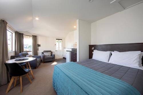 Ashford Motor Lodge في كرايستشيرش: غرفة فندقية بسرير وطاولة وكراسي