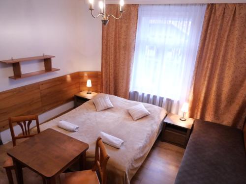 a bedroom with a bed and a table and a window at Pokoje Szczawnica Centrum - duży ogród in Szczawnica