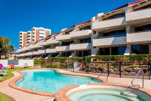 uma piscina em frente a um edifício de apartamentos em Sandrift Beachfront Apartments em Gold Coast