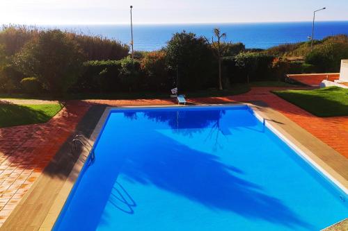 a blue swimming pool with the ocean in the background at Ericeira Sunset Lifestyle II in Ericeira