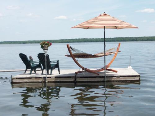 two chairs and an umbrella sitting on a dock in the water at Leech Lake Resort Bed & Breakfast in Walker