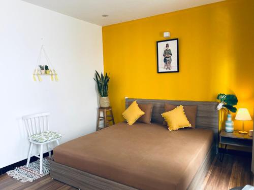 a bedroom with a bed and a yellow wall at Na Homestay in Hue
