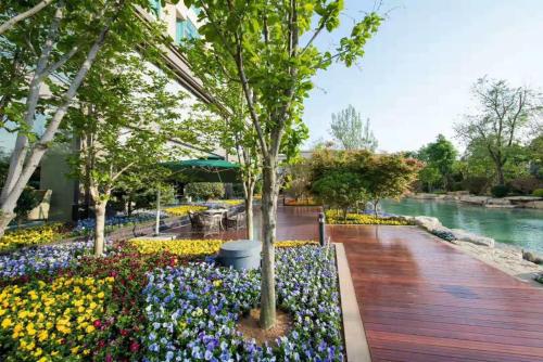 a garden with flowers and trees on a wooden deck at Wyndham Qingdao l Free Fixed-Time Shuttle Service Between Hotel and Airport & North Railway Station l Outdoor Children's Amusement Park l 1-Hour Play Snooker or Table Tennis in Qingdao