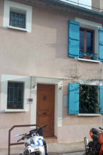 a motorcycle parked in front of a building with blue windows at Suite Privée Bed and Breakfast in Nîmes