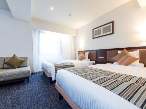 a hotel room with two beds and a chair at HOTEL MYSTAYS Fukuoka Tenjin in Fukuoka