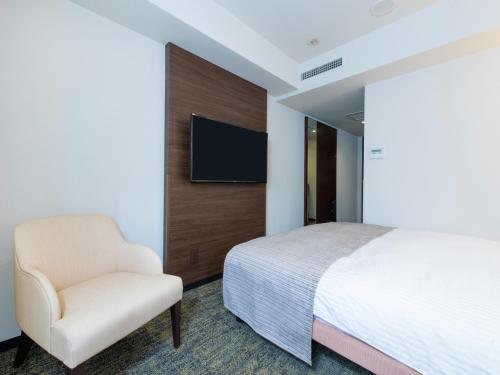 a bedroom with a bed and a chair and a tv at HOTEL MYSTAYS Fukuoka Tenjin in Fukuoka