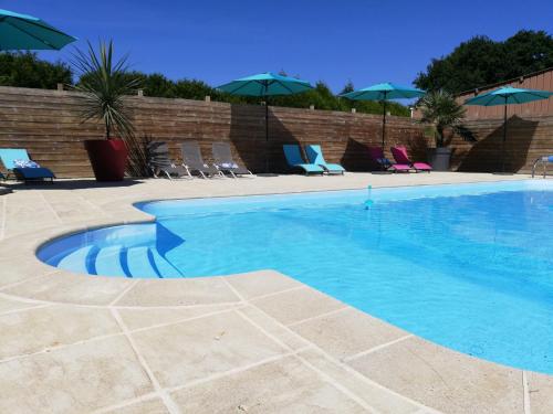 una gran piscina con sillas y sombrillas en Domaine de la Tarais, en Calorguen