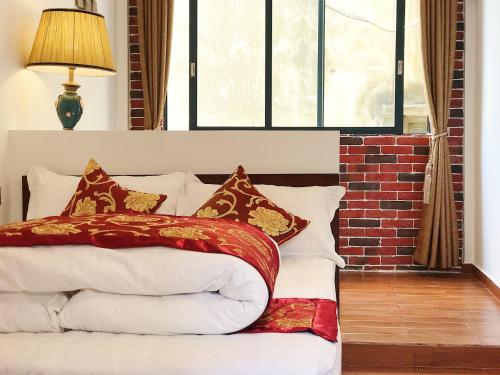 a bed with red and white pillows and a window at Mumian inn in Chaozhou