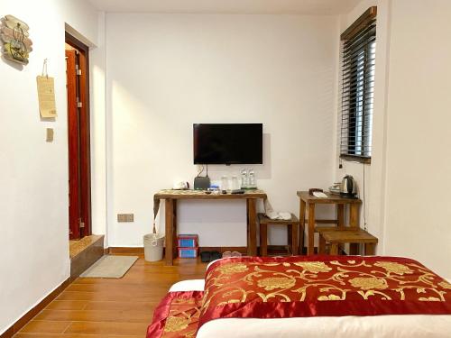 a bedroom with a bed and a desk with a television at Mumian inn in Chaozhou