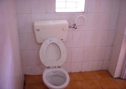 La salle de bains est pourvue de toilettes blanches et d'une fenêtre. dans l'établissement Hotel Grand Barrack, à Khandwa