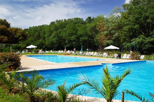 une grande piscine bleue avec chaises et parasols dans l'établissement Appartement du Commun au Château de Chanteloup, à La Croix