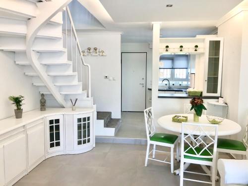 a white kitchen with a staircase and a table and chairs at Casa Stellina in Perea