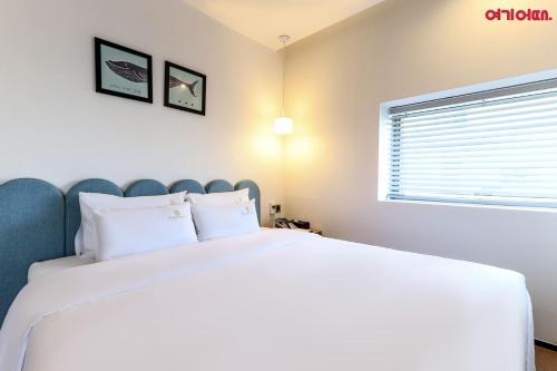 a bedroom with a large white bed and a window at Gwanganri HOTEL OCEANVIEW in Busan