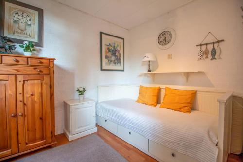 een slaapkamer met een wit bed met oranje kussens bij Casita Boschberg in Biddinghuizen
