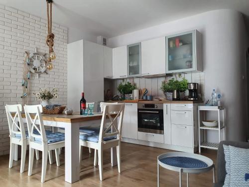uma cozinha com armários brancos e uma mesa e cadeiras em Apartament Bursztyn em Pobierowo