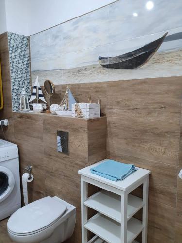 a bathroom with a toilet and a painting of a boat at Apartament Bursztyn in Pobierowo