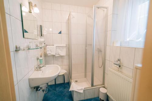 ein weißes Bad mit einem Waschbecken und einer Dusche in der Unterkunft Hotel Abenstal in Au in der Hallertau