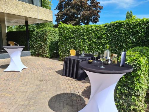 a patio with two tables with wine glasses at Amsterdam Hotel Uithoorn in Uithoorn