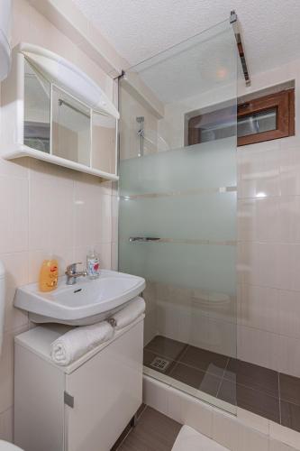 a white bathroom with a sink and a shower at Apartmani Pilaš in Dramalj